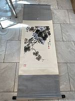 Full length of the scroll painting laid flat showing top and bottom grey fabric mount and wooden roller ends