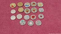 Full set of 19 Canadian collectible coins laid out on red cloth, showing various designs including poppies, maple leaf, and commemorative themes.
