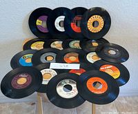 Display of 19 vintage 45 RPM vinyl records arranged on a table showing various labels and visible surface wear.