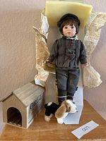 Full view of Coca-Cola boy doll standing in original packaging with dog house and plush dog beside it.
