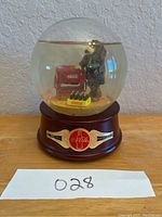 Front view of Coca-Cola musical snow globe showing clown figurine and branding details on base.