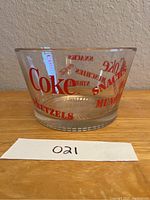 Side view of the Coca-Cola glass snack bowl showing red printed snack names and 'Coke' text.