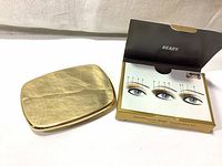 Closed gold compact case with BareMinerals logo and open instruction card showing eye makeup placement suggestions.