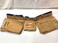 Front view of the suede leather adjustable tool belt showing the multiple pockets and metal rivets, with visible stains on the pockets.