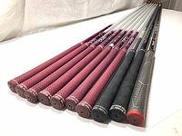 Group photo of 11 golf shafts laid side by side showing grips and shaft tops
