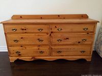 Front view of six-drawer pine dresser with scalloped base and brass drop bail pulls