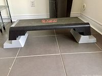 Black anti-slip textured aerobic step platform with red 'STEP Reebok' lettering and gray support blocks showing the step's structure and design.