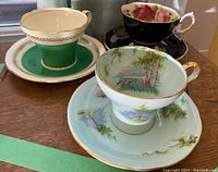 Three bone china teacups and saucers in varied designs and colors shown together on a table