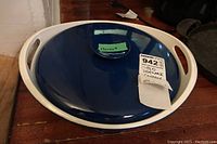 Top view of the blue enamel lid with handles visible showing size label 13x14x4 and a lot tag.
