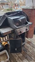 Weber Spirit gas grill with cover partially draped over top