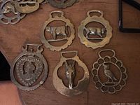 Photo showing 5 horse brass pieces with distinctive animal designs like pig, owl, horse head, and floral shapes.