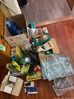 Top view of boxes and bottles of household cleaning supplies including garbage bags, compost bags, cleaning liquids, pesticides, and ice packs.