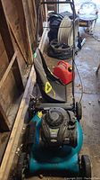 Full view of Yardworks push lawn mower with attached grass catcher bag and red jerry can placed on top