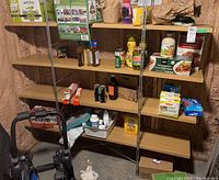 Front view of shelving unit with various pantry and miscellaneous items placed on shelves in basement environment.