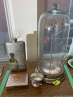 Photo showing all four items together on wooden surface: flask, glass bell jar with necklace stand inside, trinket box and pedestal dish