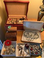 Photo showing jewelry boxes with assorted costume jewelry and buttons inside, wooden boxes, and jewelry components.