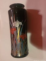 Front view of a black Japanese ceramic vase with gold-accented iris flowers painted in red, white, and blue tones.