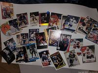 Thirty assorted sports cards laid out showcasing hockey, baseball, and basketball players in various team uniforms. Cards measure approximately 3 inches each. Includes some foil and holographic cards.