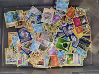 Image showing a large bin pile of over 100 loose Pokémon trading cards with various types and designs, including Energy cards and character cards.