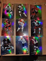 Photo of nine holographic hockey cards arranged in a 3x3 grid on a brown surface, showing different NHL players in team uniforms with holographic foil highlight.