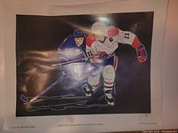 Photo of signed lithograph showing two hockey players in blue and white jerseys, signed and numbered 70/100 with noticeable wear and creases on the surface.