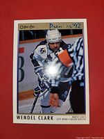 Front of O-Pee-Chee Premier '92 hockey card showing Wendel Clark skating in Toronto Maple Leafs white uniform with helmet and hockey stick.