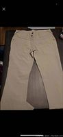Full view of beige twill travel pants laid flat showing front side with pockets and button fly detail.