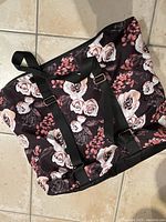 Full view of the soft rectangular floral bag with black adjustable straps, showing large rose and flower print covering the surface.
