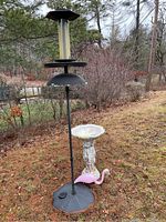 Metal bird feeder with black base, multiple feeding sections outdoors