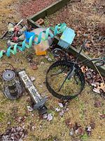 Overview of lot showing metal stand, bird feeders, solar lights, and ornament on grass with leaves and mulch