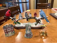 Artisan bird figurines with various miniature building figurines on table