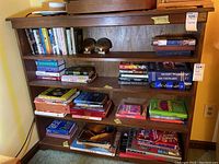 Full front view of wood bookcase with books and other items on shelves, showing overall structure and some surface wear.