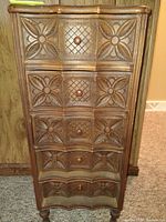 Front view of vintage wooden chest showing five drawers with floral and lattice carved designs.