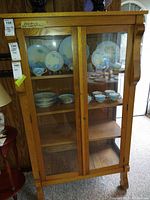 Front view of oak display cabinet showing two glass doors, interior shelves and overall condition