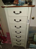 Front view of the full seven-drawer white lingerie chest with wood top and metal handles.