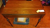 Front view of the wooden drop-leaf side table showing its rectangular top and turned legs.