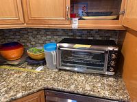 Wide view of toaster oven and adjacent kitchenware showing bowls, pitcher, and gadgets