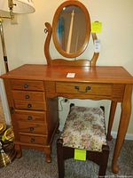 Vanity table with oval mirror and floral upholstered stool from front angle