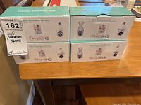 Four boxed WiFi Panorama Cameras arranged on a table, showing front and side views of packaging including camera images and branding.