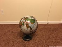 Front angle of the world globe showing Europe, Africa, and parts of Asia and South America on a beige carpet against a beige wall.
