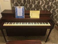 Front view of the antique upright piano with two pieces of sheet music on the music stand.