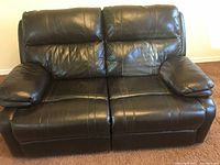 Front view of the dark brown leather two-seat recliner sofa showing padded armrests and cushions.