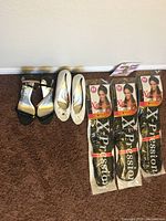 Photo showing two pairs of women's shoes and three sealed packs of X-Pression braided hair extensions arranged on carpeted floor against a wall.