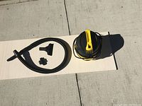 Stanley wet/dry vacuum, hose and attachments laid out on a board outdoors, side view.