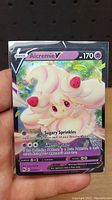 Front of the Alcremie V Pokémon TCG card showing character, attacks, HP and energy types.