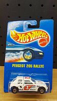 Front of sealed Hot Wheels Peugeot 205 Rallye car blister card packaging showing car inside and Hot Wheels branding.