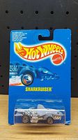 Front view of sealed Hot Wheels Sharkruiser 1990 die-cast car in original blue packaging with logo and name.