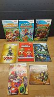 Eight Nintendo Wii game manuals laid out on a wooden table, titles visible including Monkey Ball Banana Blitz, New Super Mario Bros. Wii, Donkey Kong Country Returns, Legend of Zelda, Mario Bros., TMNT, Bakugan, and Link's Crossbow Training.