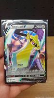 Front of Aegislash V Pokémon card in protective sleeve showing the artwork, health points, and attack details