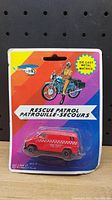 Photo of sealed vintage diecast Rescue Patrol red van toy in original Mattel packaging with colorful diagonal stripes and illustration of a police motorbike rider.